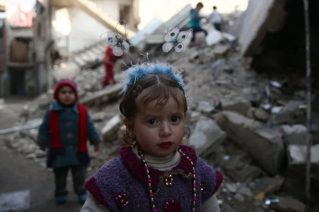 A girl wearing a butterfly headband poses for a picture near damaged buildings in the rebel held besieged city of Douma, in the eastern Damascus suburb of Ghouta, Syria January 19, 2017. (Photo by Bassam Khabieh/Reuters)