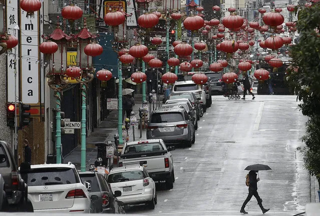 A woman walks below red lanterns hanging on Grant Avenue in San Francisco's Chinatown, Monday, February 4, 2019. A winter storm sweeping across California and Nevada has dumped at least 8 feet (2.4 meters) of snow over the past two days, with more expected. (Photo by Jeff Chiu/AP Photo)