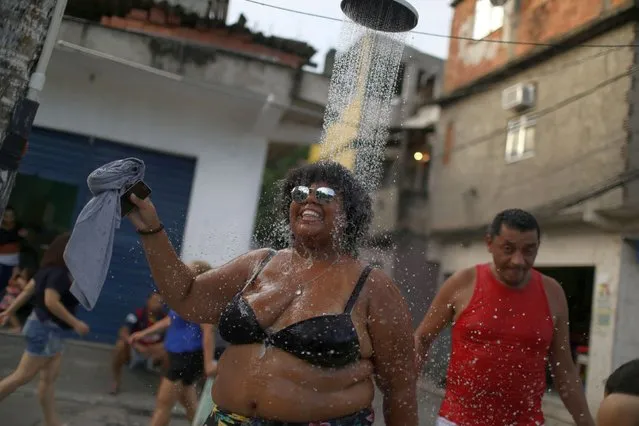 A reveller refreshes herself with a shower during the annual “Se Benze que da” block party, created by late councilwoman Marielle Franco, in the Mare slum in Rio de Janeiro, Brazil on February 23, 2019. (Photo by Pilar Olivares/Reuters)