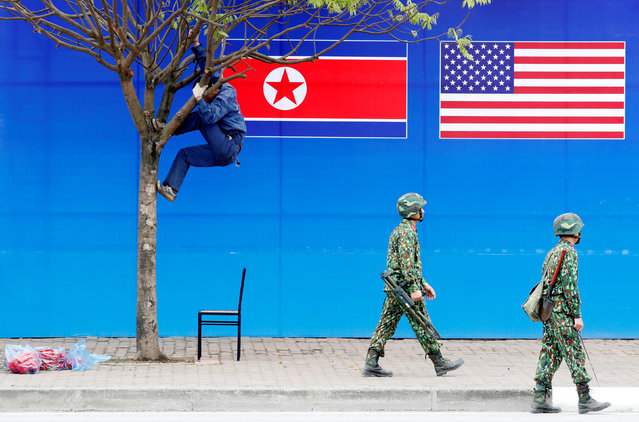 A worker is seen on a tree next to a banner showing North Korean and U.S. flags ahead of the North Korea-U.S. summit in Hanoi, Vietnam, February 25, 2019. (Photo by Kim Kyung-Hoon/Reuters)