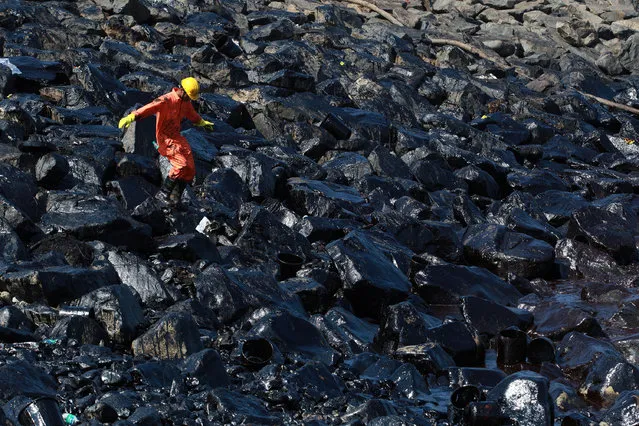 An emergency worker walks amidst oil deposits as he cleans oil from the shoreline of Ennore Port following a collision between two oil tankers, in Chennai, India February 2, 2017. (Photo by Reuters/Stringer)