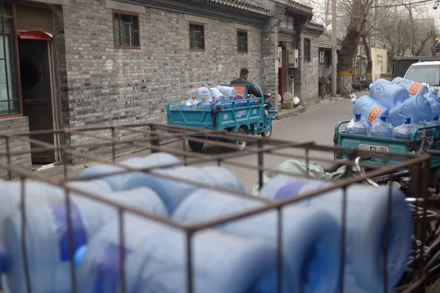 A courier riding an electric tricycle with barrels of water leaves a shop selling bottled water in an alley in Beijing on March 22, 2016. Environmental watchdog Greenpeace warned on March 22 the world's coal plants are “deepening” the global water crisis as the water consumed by them can meet the basic needs of one billion people. (Photo by Wang Zhao/AFP Photo)