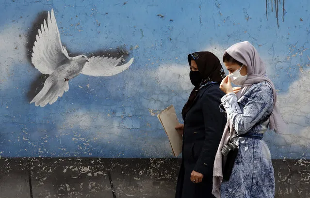 Two Iranian women walk past a mural depicting a flying dove at a street in Tehran, Iran, 01 November 2021. The Iranian Ministry of Foreign Affairs announced that the Islamic Republic is ready to return to nuclear talks in Vienna before the end of November. Iran also proposed to the US administration to lift the sanctions and to start negotiations. Iran is facing an economic crisis under US heavy sanctions following the United States' withdrawal from a nuclear deal in 2018. (Photo by Abedin Taherkenareh/EPA/EFE)