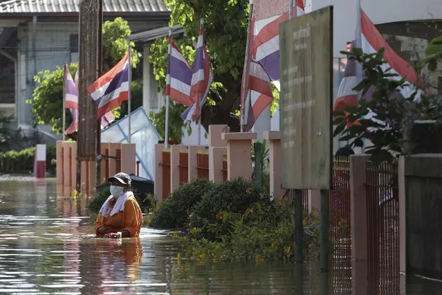 A woman wades through floodwaters in Ayutthaya province, north of Bangkok, Thailand, Monday, October 4, 2021. As flood waters continued to inundate areas in northern and central Thailand and were starting to hit low-lying areas in the capital, Thai officials were looking warily ahead Tuesday the possibility of more storms this month, but were optimistic the devastation of a decade ago would not be repeated. (Photo by Nathathida Adireksarn/AP Photo)