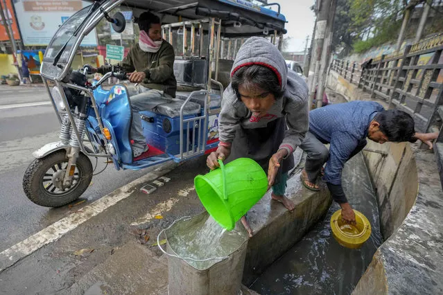 People collect water from an open drain on World Water Day in Guwahati, India, Friday, March 22, 2024. (Photo by Anupam Nath/AP Photo)