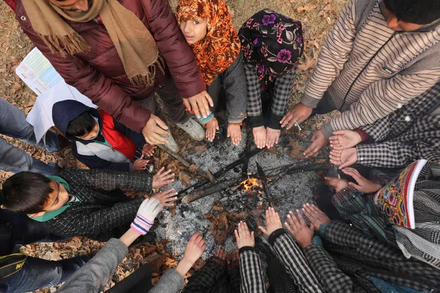 Teacher and students of a government school warm themselves during community classes at a village in Central Kashmir’s Ganderbal​ district, outskirts of Srinagar, India, 02 December 2021. (Photo by Farooq Khan/EPA/EFE)