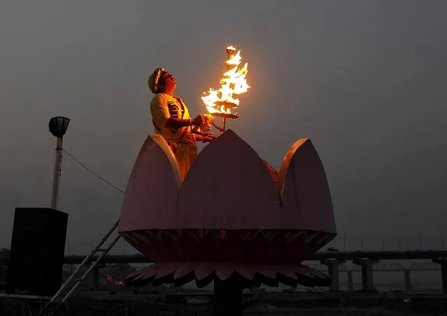 A Hindu priest holds an oil lamp as he prays during a ritual known as Aarti on the occasion of Somvati Amavasya on the banks of the Ganges river in Allahabad, India, May 18, 2015. Hindu devotees pray for the souls of their departed ancestors during the occasion. (Photo by Jitendra Prakash/Reuters)