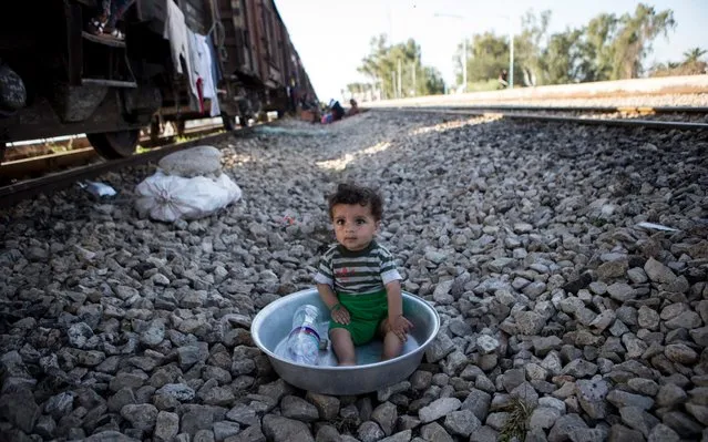 A boy sits beside a freight train cabin in a flood-hit village called Bamdezh in Khuzestan province, Iran, on April 10, 2019. Residents of Bamdezh village have been relocated to a freight train cabin by the authorities after their houses were surrounded by flood. (Photo by Ahmad Halabisaz/Xinhua News Agency)