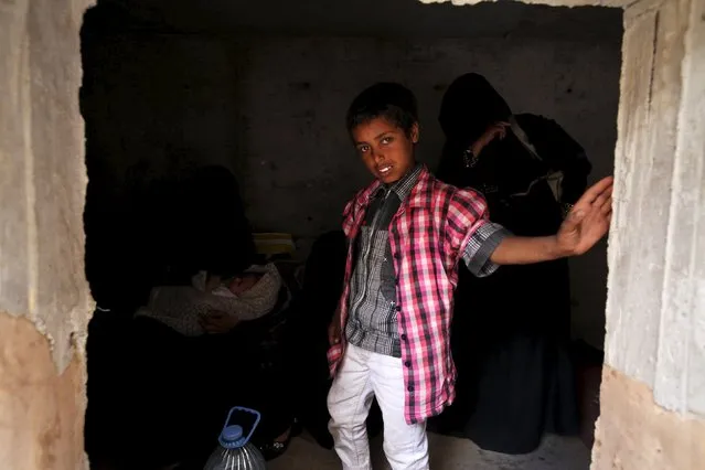 A boy stands next to his mother's inside an underground water tunnel with other displaced Yemeni families, after they were forced to flee their home due to ongoing air-strikes carried out by the Saudi-led coalition in Sanaa May 2, 2015. (Photo by Mohamed al-Sayaghi/Reuters)