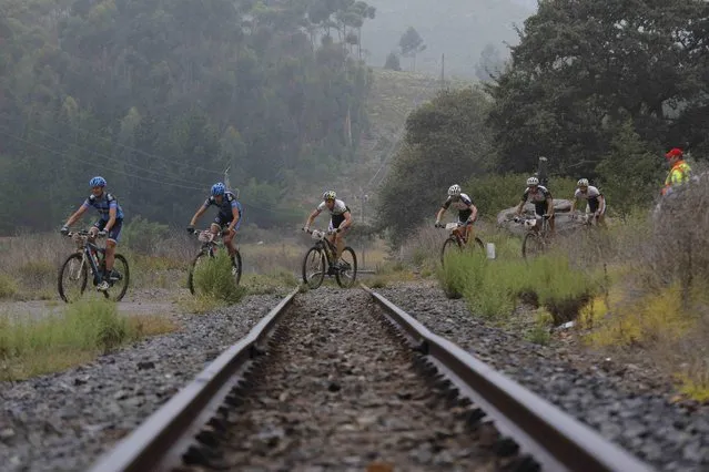 The professional peloton crosses railway tracks in an ever changing landscape during stage 6 of the annual ABSA Cape Epic mountain bike stage race, Elgin, South Africa, 29 March 2014. (Photo by Kim Ludbrook/EPA)