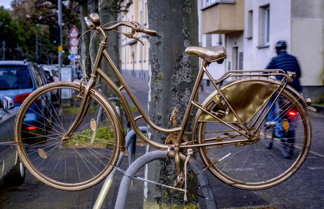 A golden painted bicycle is photographed in the city centre of Frankfurt, Germany, Thursday, April 25, 2024. Unknown people have painted several bicycles and scooters in golden color all over the city. (Photo by Michael Probst/AP Photo)