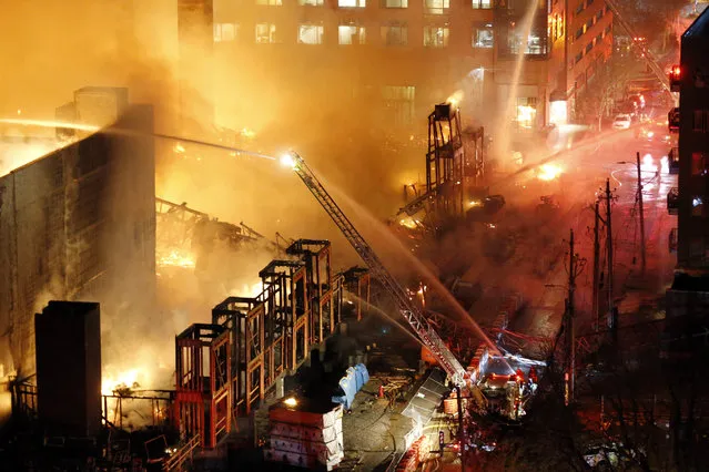 Firefighters battle a five-alarm fire burning an apartment building and surrounding structures in downtown Raleigh, N.C., Thursday night, March 16, 2017. Fire was consuming an apartment building under construction. The cause of the fire is under investigation. (Photo by Chris Seward/The News & Observer via AP Photo)
