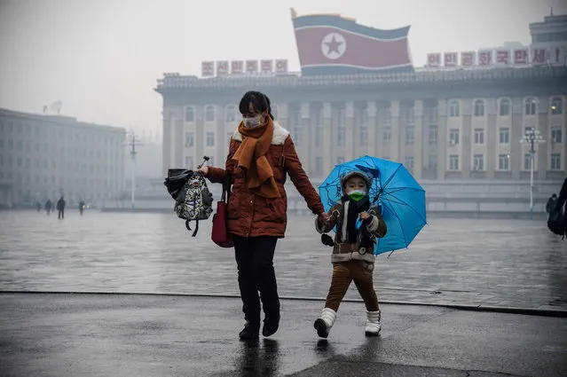 A boy and his mother walk in Kim Il Sung Square in Pyongyang on December 10, 2021. (Photo by Kim Won Jin/AFP Photo)