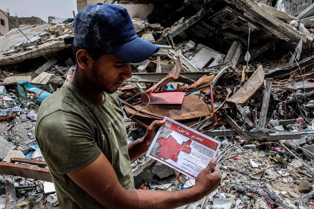 A man holds one of the flyers dropped by the Israeli military on the northern Gaza Strip urging people to “temporarily evacuate to shelters in western Gaza City” on May 11, 2024 amid the ongoing conflict in the Palestinian territory between Israel and Hamas. (Photo by AFP Photo/Stringer)