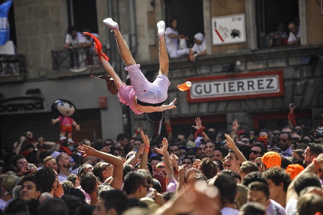 Revelers celebrate during the launch of the “Chupinazo” rocket, to celebrate the official opening of the 2015 San Fermin Fiestas, in Pamplona, northern Spain, Monday, July 6, 2015. (Photo by Alvaro Barrientos/AP Photo)