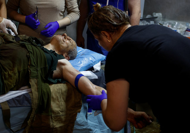 Medics provide treatment to injured Ukrainian serviceman Vitalii at a stabilization point near a front line in Kharkiv Region, Ukraine on June 2, 2024. (Photo by Valentyn Ogirenko/Reuters)