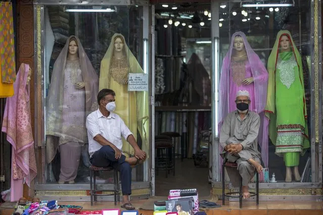 Kashmiri shopkeepers wearing face masks as a precaution against the coronavirus wait for customer outside their shop in Srinagar, Indian controlled Kashmir, Sunday, August 1, 2021. (Photo by Mukhtar Khan/AP Photo)