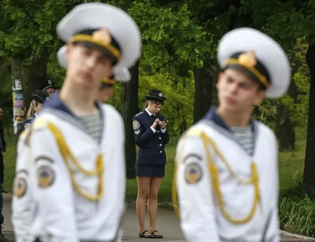 A policewoman uses her mobile phone as navy honor guards stand near of a World War Two memorial during celebrations to mark Victory Day in the Black Sea port of Odessa May 9, 2014. Ukraine celebrates the 1945 victory over Nazi Germany during World War Two on May 9. (Photo by Gleb Garanich/Reuters)