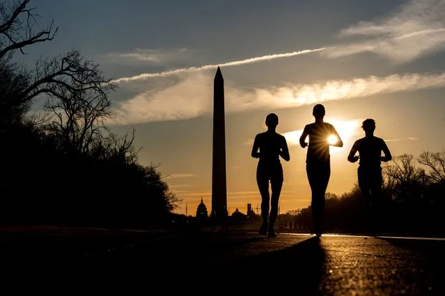 People run along the National Mall at sunrise in Washington, DC, on March 15, 2022. (Photo by Stefani Reynolds/AFP Photo)