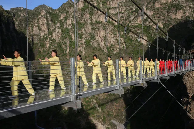People practise tai chi on a suspension bridge in Beijing, China on April 23, 2017. (Photo by Reuters/China Stringer Network)