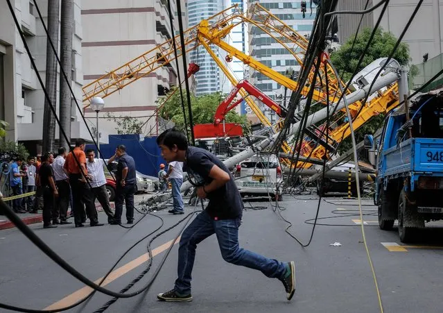 A Filipino hurries to cross past damaged wires after a construction crane collapsed in Makati City, south of Manila, Philippines, early 26 May 2016. According to a statement by AM Oreta Construction Company, a construction crane collapsed affecting a few electric posts and high tension wires. A taxi driver and a bicycle rider were hurt and brought to the nearest hospital. The cause if the accident is under investigation. (Photo by Mark R. Cristino/EPA)