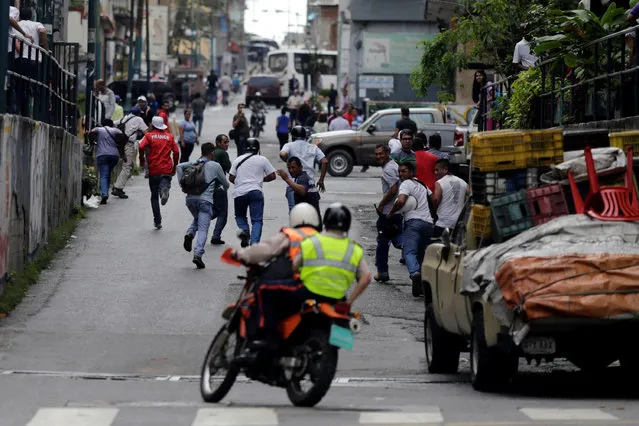 People run away from police (on motorcycle) during riots for food in Caracas, Venezuela, June 2, 2016. (Photo by Marco Bello/Reuters)