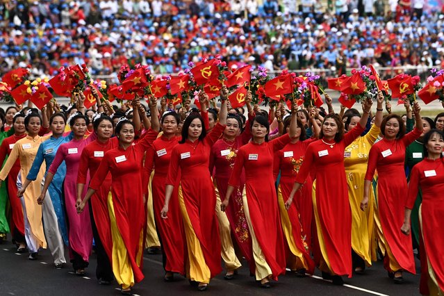 Women wave flags during official celebrations of the 70th anniversary of the 1954 Dien Bien Phu victory over French colonial forces at a stadium in Dien Bien Phu city on May 7, 2024. War veterans, soldiers and dignitaries gathered in Vietnam's Dien Bien Phu on May 7 to mark the 70th anniversary of the battle that ultimately brought an end to the French empire in Indochina. (Photo by Nhac Nguyen/AFP Photo)