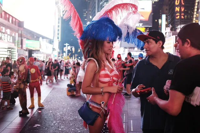 A semi-nude model speaks with men about a tip after posing for a photo in Times Square on August 19, 2015 in New York City. (Photo by Spencer Platt/Getty Images)