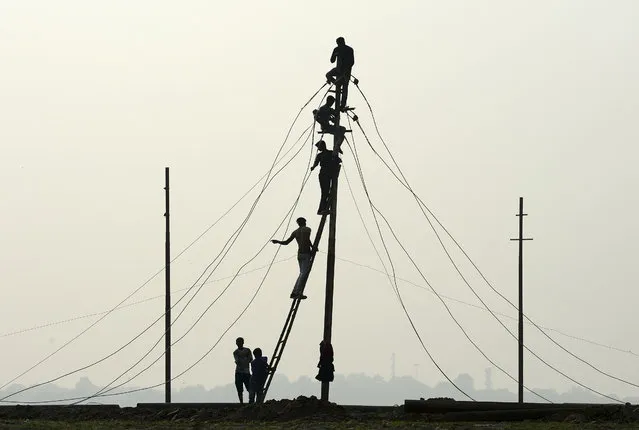 Indian workers install electricity cables on the banks of the river Ganges in preparation for the annual Hindu religious fair of Magh Mela in Allahabad on December 5, 2019. The Magh Mela is held every year on the banks of Triveni Sangam – the confluence of the three great rivers Ganga, Yamuna and the mystical Saraswati – in Allahabad during the Hindu month of Magh which corresponds to mid January - mid February. (Photo by Sanjay Kanojia/AFP Photo)