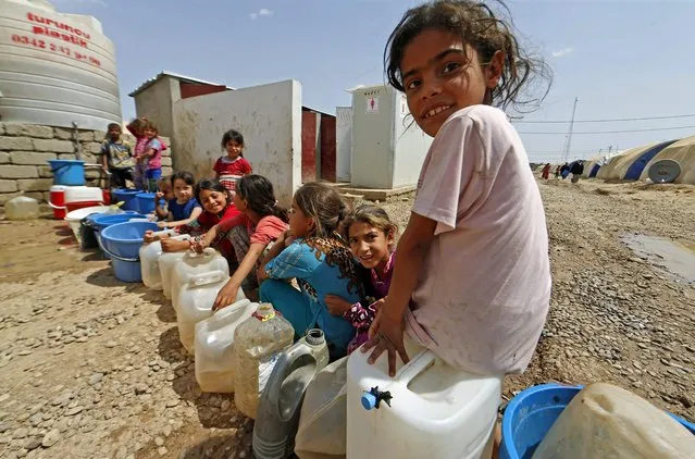 Displaced Iraqi children wait in line for water rations at the Hammam al-Alil camp for internally displaced people south of Mosul on May 26, 2017, as government forces continue their offensive to retake the city of Mosul from Islamic State (IS) group fighters. (Photo by Karim Sahib/AFP Photo)