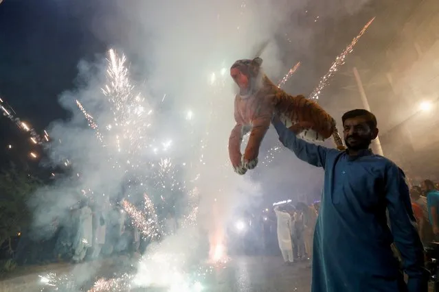A supporter of the Pakistan Muslim League-Nawaz (PML-N) holds a stuffed tiger as he celebrates after Shehbaz Sharif was sworn in as the country's prime minister, in Rawalpindi, Pakistan on April 11, 2022. (Photo by Akhtar Soomro/Reuters)