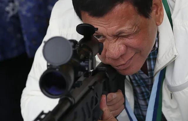Philippine President Rodrigo Duterte checks the scope of a Chinese-made CS/LR4A sniper rifle during the presentation of thousands of rifles and ammunition by China to the Philippines Wednesday, June 28, 2017, at Clark Airbase in northern Philippines. According to a government statement the firearms form “part of the military aid package by China in relation with the emerging threat of terrorism and piracy in southern Philippines”. (Photo by Bullit Marquez/AP Photo)