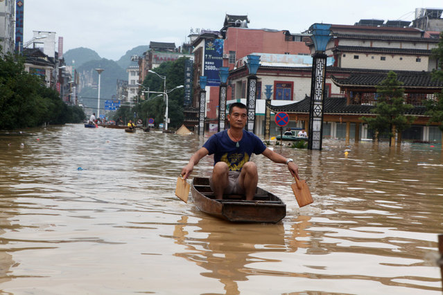 A man makes his way with a wooden boat through a flooded area in Liuzhou, Guangxi province, China on July 3, 2017. (Photo by Reuters/Stringer)