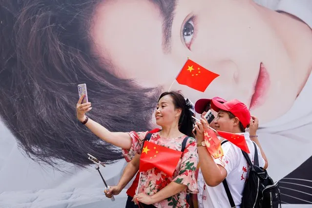 Pro-China supporters pose for a photo in front of an advertisement of singer Anson Lo, a member of the Hong Kong boy group Mirror, on Chinese National Day, in Hong Kong, China, October 1, 2021. (Photo by Tyrone Siu/Reuters)