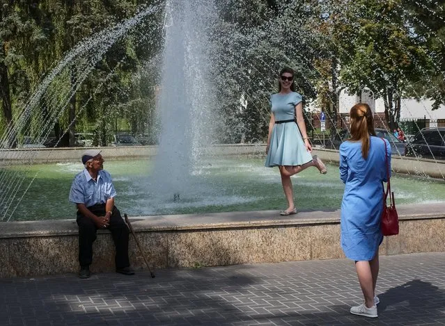 A woman poses for pictures as a man looks on in central Chisinau, Moldova on September 10, 2019. (Photo by Gleb Garanich/Reuters)