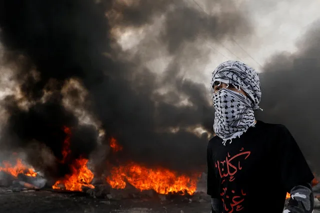 A Palestinian demonstrator looks on as tires burn during a protest against U.S. President Donald Trump's Middle East peace plan, near the Jewish settlement of Beit El in the Israeli-occupied West Bank on January 30, 2020. (Photo by Mohamad Torokman/Reuters)