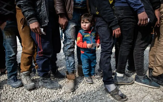 Displaced Syrians wait in a queue as an NGO delivers bread as they wait to receive humanitarian aid in a stadium which has been turned into a makeshift refugee shelter on February 19, 2020 in Idlib, Syria. Turkey’s President Recep Tayyip Erdogan said in a speech on Tuesday that he would order “imminent operations in Syria’s Idlib if Damascus fails to withdraw behind Turkish positions”. The threat comes after Syria’s government and its ally Russia rejected demands to pull back to ceasefire lines agreed upon in the 2018 Sochi accord. More than 900,000 civilians have been displaced by fighting in or around Idlib since December 1. Idlib is the last rebel stronghold of fighters trying to overthrow Syrian President Bashar al-Assad and in the past years has become the last safe haven for civilians displaced by fighting in other areas of Syria, its population has doubled to close to three million people, many of whom are now fleeing the government offensive towards overcrowded camps close to the Turkish border amid freezing conditions, creating a humanitarian disaster. (Photo by Burak Kara/Getty Images)