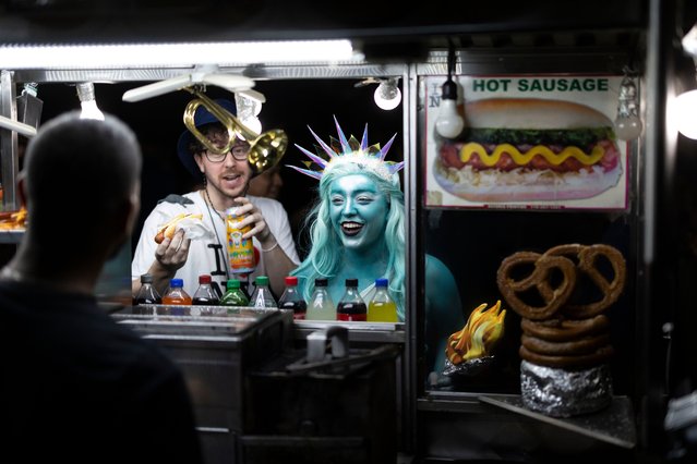 A person dressed as the Statue of Liberty pays for a hot dog on a side street near the 51st Annual Village Halloween Parade in New York, New York, USA, 31 October 2024. The annual holiday parade passes through the city's Greenwich Village neighborhood and claims to be the largest Halloween parade in the world. (Photo by Justin Lane/EPA/EFE)