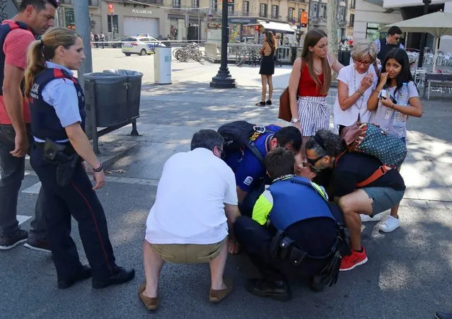 A person is treated in Barcelona, Spain, Thursday, August 17, 2017 after a white van jumped the sidewalk in the historic Las Ramblas district, crashing into a summer crowd of residents and tourists and injuring several people, police said. (Photo by Oriol Duran/AP Photo)