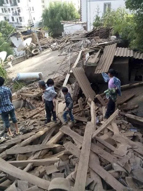 People walk among debris after an earthquake hit Ludian county, Yunnan province August 3, 2014. A magnitude 6.5 earthquake struck southwestern China on Sunday, killing at least 150 people in a remote mountainous area of Yunnan province, causing some buildings, including a school, to collapse, Xinhua News Agency reported. (Photo by Reuters/China Daily)