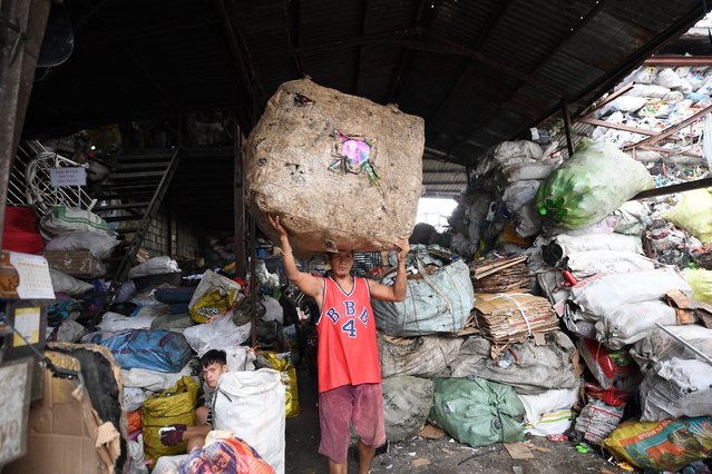 A worker carries a bale full of plastics and tin cans for segregation at a junk yard in Manila on November 7, 2024. (Photo by Ted Aljibe/AFP Photo)