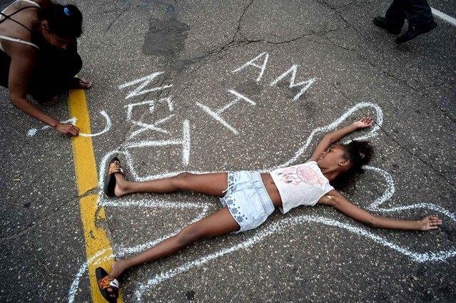 Tia Williams, left, and her daughter Aissa create a display on the street outside the Minnesota governor's official residence Thursday, July 7, 2016, in St. Paul, Minn., as people gathered to protest the shooting death of Philando Castile by police. (Photo by Richard Tsong-Taatarii/Star Tribune via AP Photo)