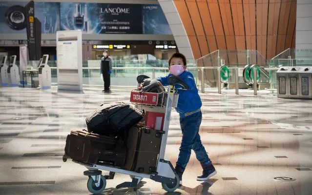 A young passenger wearing face mask push a cart with luggage in the recently opened Beijing Daxing International Airport, China, on March 03, 2020. As the novel coronavirus expands worldwide and bookings decrease, airlines around the world face a big crisis. (Photo by Andrea Verdelli/Getty Images)