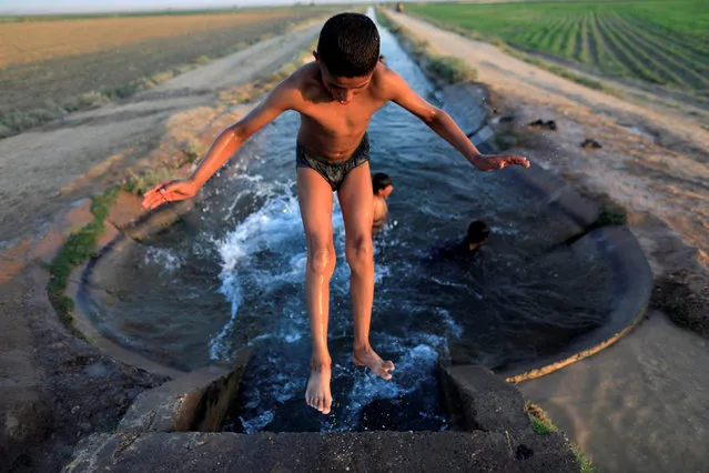 A boy cools off in an irrigation canal on the outskirts of the city in Raqqa, Syria on August 16, 2017. (Photo by Zohra Bensemra/Reuters)