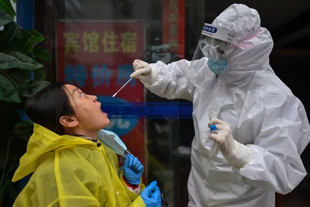 A medical worker takes a swab sample from a person to be tested for the COVID-19 novel coronavirus in Wuhan, China's central Hubei province on March 29, 2020, a day after travel restrictions into the city were eased following the outbreak. Wuhan, the central Chinese city where the coronavirus first emerged last year, partly reopened on March 28 after more than two months of near total isolation for its population of 11 million. (Photo by Hector Retamal/AFP Photo)