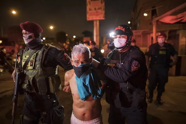 Policemen detain a man for violating the curfew declared by the government amid coronavirus concerns in El Callao, on the outskirts of Lima, Peru, Wednesday, April 8, 2020. (Photo by Rodrigo Abd/AP Photo)