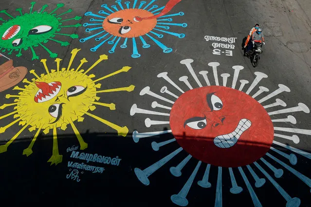A motorist rides past a graffiti painted on a road to raise awareness about the COVID-19 coronavirus during a government-imposed nationwide lockdown as a preventive measure against the COVID-19 coronavirus in Chennai on April 13, 2020. (Photo by Arun Sankar/AFP Photo)
