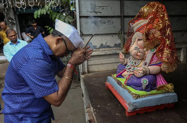 Indian devotee offers prayer to an idol of the elephant-headed Hindu God Ganesha, before taking it to their home on the occasion of Ganesh Chaturthi, in Mumbai, India, 31 August 2022. The Ganesh Chaturthi festival is a ten-day long event which is celebrated all over India. During the Ganpati festival, that is celebrated as the birthday of Lord Ganesha, idols of the Hindu deity are worshipped at hundreds of pandals or makeshift tents before they are immersed into water bodies. (Photo by Divyakant Solanki/EPA/EFE)