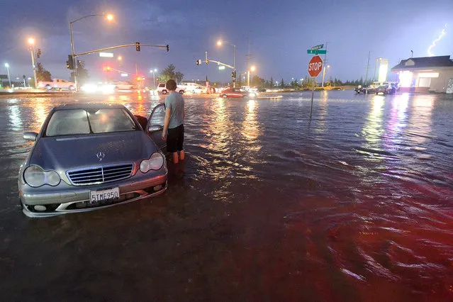 A motorist stands in water near Bear Valley Outerhighway South, Tuesday, September 8, 2015, in Hesperia, Calif. The National Weather Service issued a flash flood warning and severe thunderstorm warning for the area on Tuesday night. (Photo by David Pardo/The Victor Valley Daily Press via AP Photo)