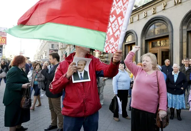 A man holds a portrait of Belarussian President Alexander Lukashenko, who is a candidate in the upcoming presidential elections, and a Belarussian national flag during a meeting between opposition leaders and people, in central Minsk, September 10, 2015. The Belarussian presidential election is scheduled to be held on October 11, 2015. (Photo by Vasily Fedosenko/Reuters)